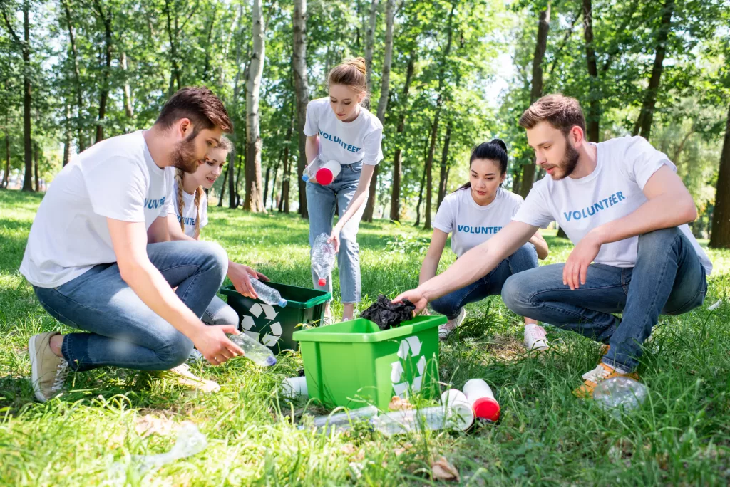 volunteers working in a forest picking up garbage and recycling